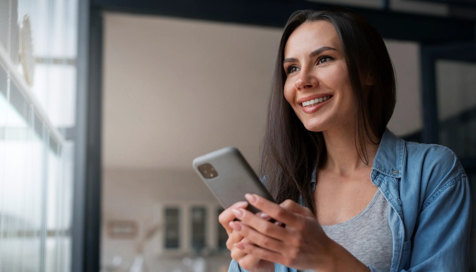 Mulher sorrindo ao usar o celular conectada à internet da Jactos Fibra